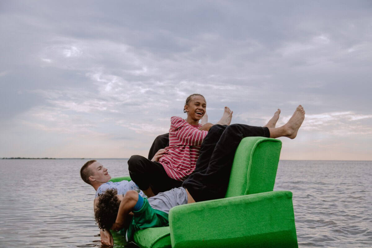 Three teenagers on a green sofa in the sea